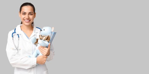Portrait of female pediatrician on grey background with space for text © Pixel-Shot