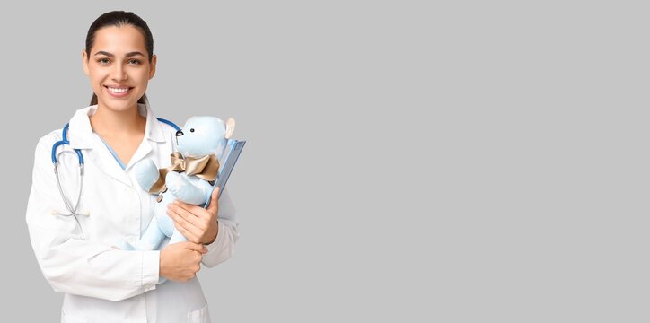 Portrait of female pediatrician on grey background with space for text
