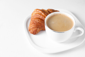 Breakfast time. Fresh croissant and coffee on white background. Space for text