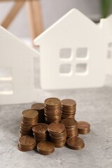 House models and stacked coins on grey table, selective focus