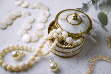 Mother-of-pearl gold box with pearl jewelry on a white table - 768353826