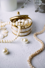 Mother-of-pearl gold box with pearl jewelry on a white table - 768353844