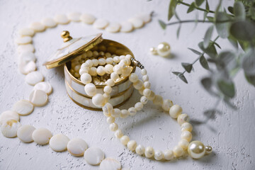 Mother-of-pearl gold box with pearl jewelry on a white table