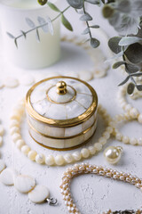 Mother-of-pearl gold box with pearl jewelry on a white table