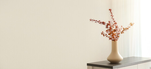 Vase with beautiful blossoming branches on cabinet