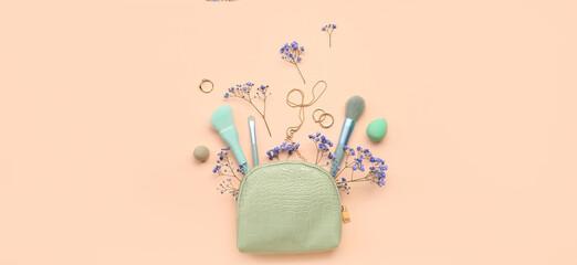 Cosmetic bag with female accessories and flowers on pink background