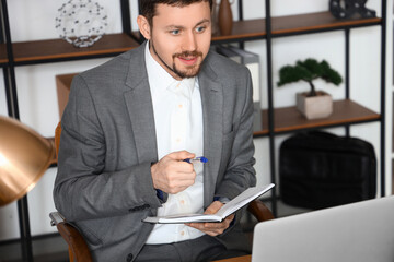 Male tutor with notebook giving online lesson at home