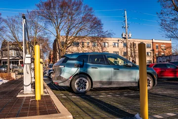 Fotobehang green economy:  electric station wagon / light suv electric vehicle connected  to a charging in a public parking lot shot in toronto beaches in spring © Michael Connor Photo