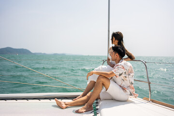 Asian young romantic couple looking at beautiful view during yachting. 