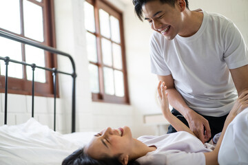 Asian attractive man tickles his girlfriend while lying down on bed. 