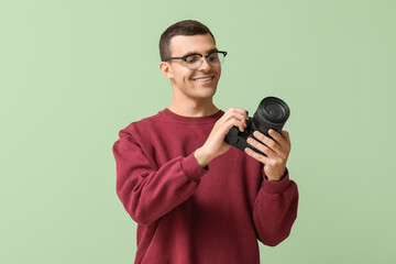 Naklejka premium Happy male photographer with modern camera on green background