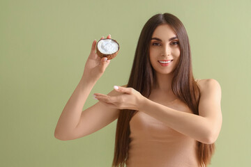 Beautiful young woman with shell of coconut oil on green background