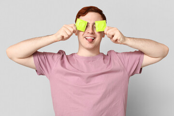 Funny young man with condoms on grey background. Safe sex concept