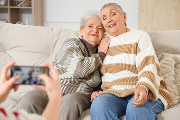 Senior female friends being photographed at home