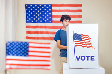 A man in the voting booth casting his vote to choose the new President of the United States. The polling location is adorned with American flags. American Presidential Election.