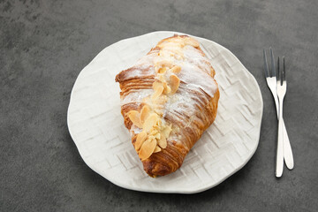 Almond Croissant with sprinkling icing sugar on white plate 
