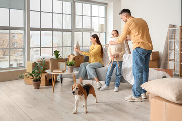 Happy family with Beagle dog packing things in room on moving day