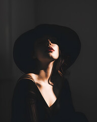 A woman in a black hat is gazing upwards in the shadows