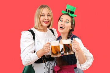 Happy women with beer celebrating St. Patrick's Day on red background