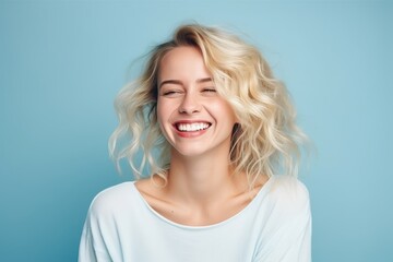 Portrait of a beautiful young woman with blond hair on blue background