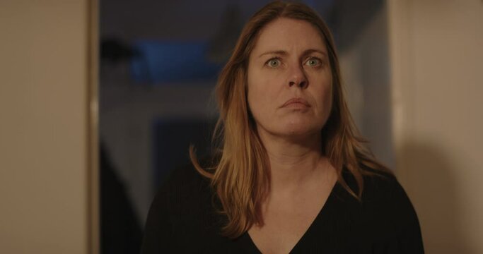 Frightened woman looking at something off screen, she gets scared and flees her home