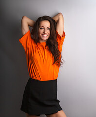 Beautiful young relaxing smiling woman in casual clothing looking with arms behind head in orange casual shirt on grey studio background on empty copy space. Closeup - 768368845