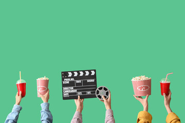 Many hands with movie clapper, buckets of popcorn and drinks on green background