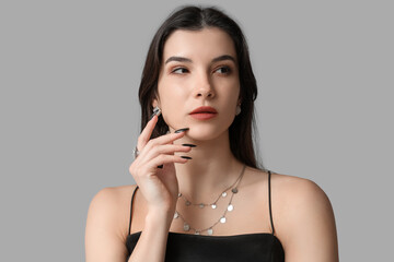 Obraz premium Beautiful young woman with stylish jewelry on grey background