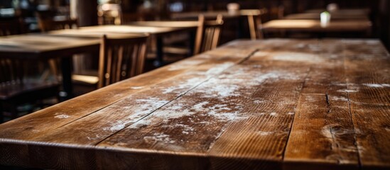 Numerous wooden tables and chairs are arranged neatly in a bustling restaurant, creating a warm and...