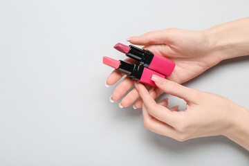 Female hands with lipsticks on grey background