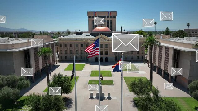 Envelopes with ballots for election over Arizona capitol building. Aerial shot of American, AZ, and POW flags waving at government building. Presidential election and voting theme.
