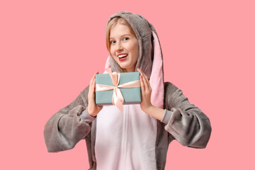 Beautiful young happy woman in bunny costume with gift box on pink background. Easter celebration