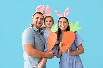 Happy family in Easter bunny ears with paper carrots on blue background