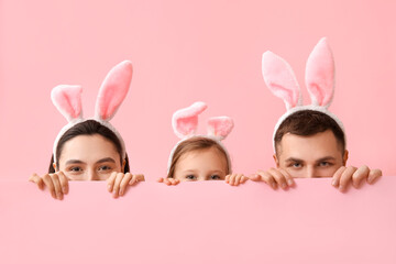 Happy family in Easter bunny ears hiding on pink background