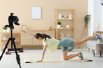 Sporty female blogger exercising and recording video at home