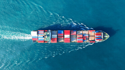 Aerial view of cargo ship with contrail in the ocean sea ship carrying container and running from...