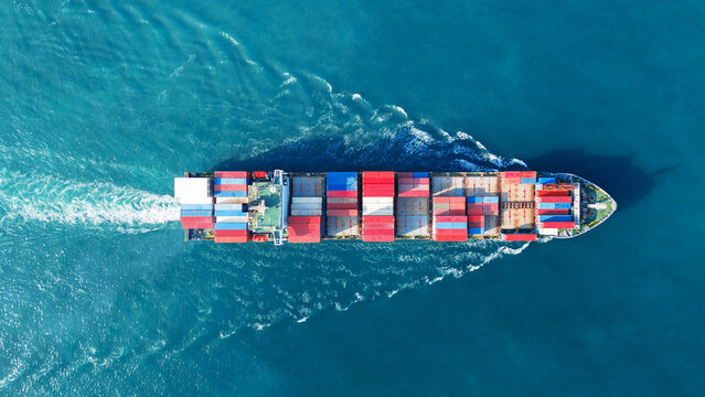 Aerial view of cargo ship with contrail in the ocean sea ship carrying container and running from container international port smart freight shipping by ship service