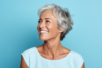 Portrait of happy senior woman looking away and smiling against blue background