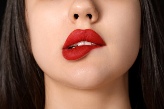 Young woman with red lips on black background, closeup