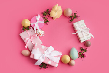 Fototapeta na wymiar Easter wreath made of gift boxes, eggs and bunny figure on pink background