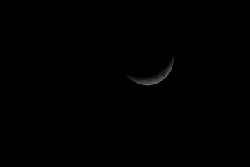 A sliver of a crescent moon in the night sky
