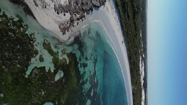 Vehicle driving along Wylie Bay Rock beach, Esperance area in Western Australia. Aerial forward and vertical format. Sky for copy space