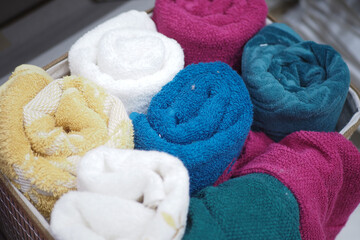 A storage basket made of wood filled with an assortment of towels
