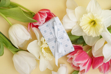 Gift box with beautiful tulips and daffodil flowers on yellow background