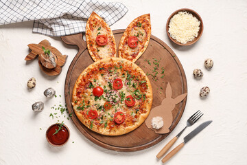 Board with Easter pizza with bunny ears, eggs, cheese and sauce on white grunge background