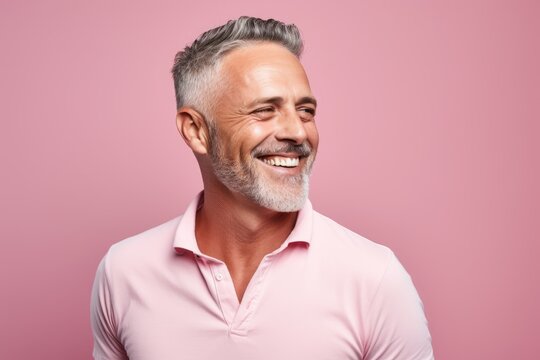 Cheerful senior man looking at camera and smiling while standing against pink background