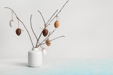 Branches with Easter eggs in vase on white background