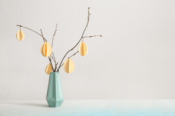 Branches with Easter paper eggs in vase on white background