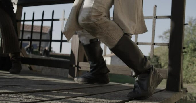 Knights feet hugging edge of bridge as he fights off men