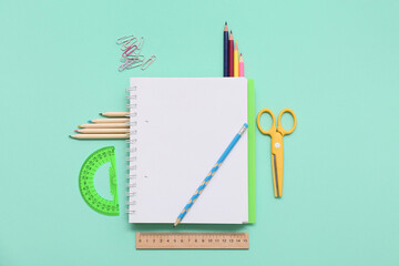 Notebook, pencil and scissors on turquoise background. Top view